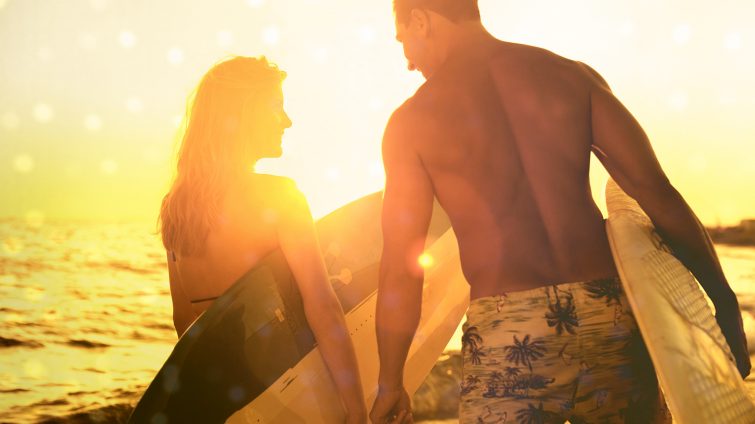 Mann und Frau mit Surfbrett im Sonnenuntergang