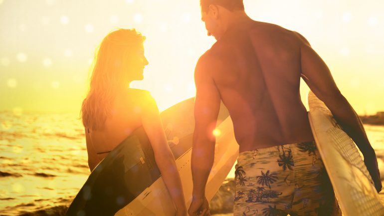 mann und frau mit surfbrett im sonnenuntergang